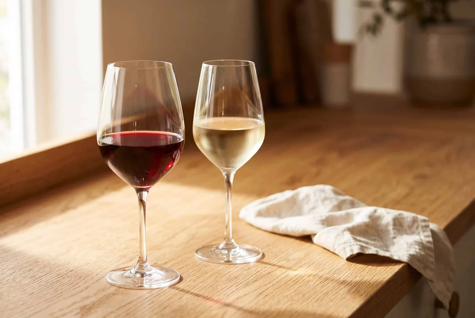 A glass of dry red wine and a glass of dry white wine on a wooden table